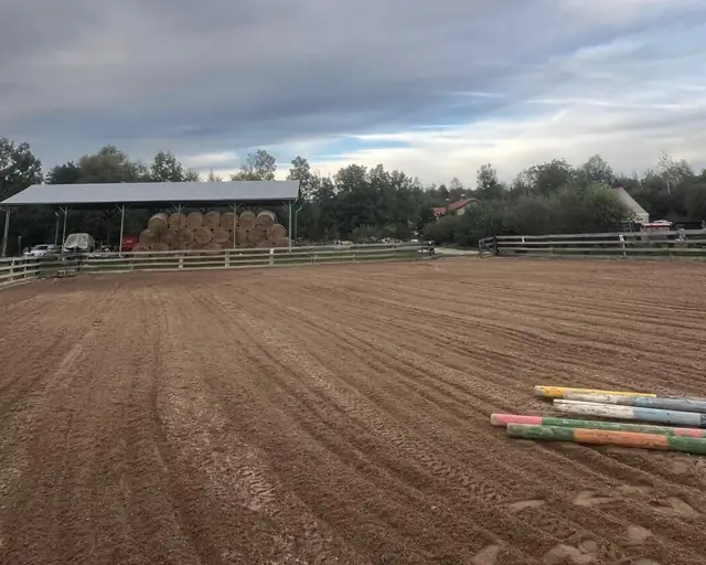 Písková jízdárna 20 × 40 m, v pozadí kryté seníky