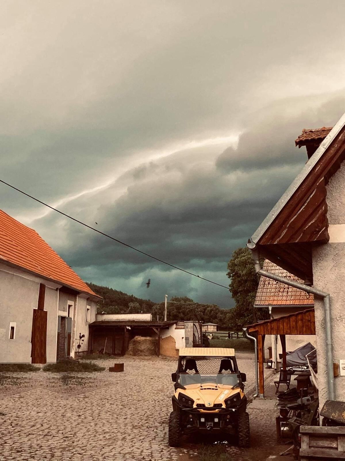 Dvůr areálu se stájemi a bouřková obloha nad údolím
